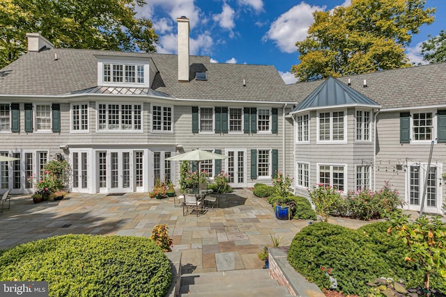 back of house with a standing seam roof, a patio, french doors, and a chimney