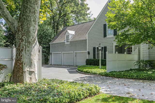 exterior space with an attached garage, driveway, and fence