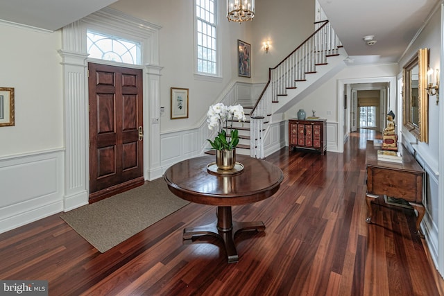 foyer entrance with stairs, crown molding, dark wood-style floors, and a decorative wall