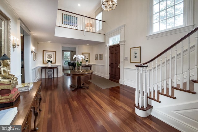 entryway featuring dark wood-type flooring, a wealth of natural light, wainscoting, and stairway