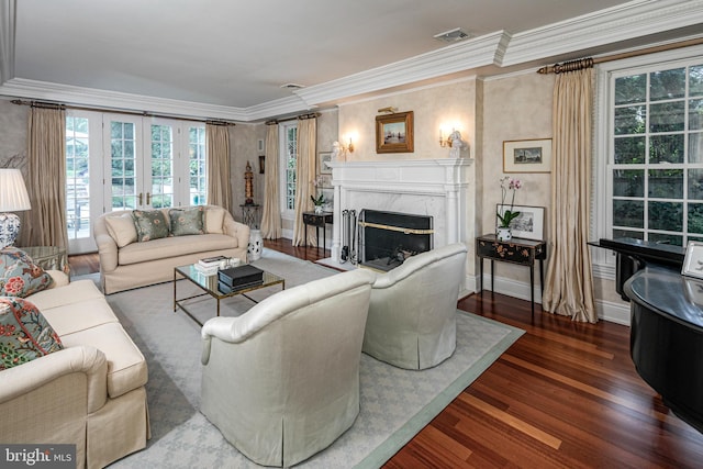 living room featuring crown molding, a high end fireplace, visible vents, and dark wood finished floors