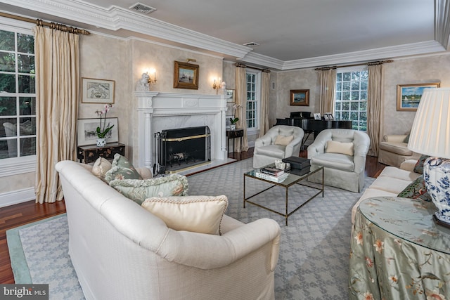 living room with crown molding, wood finished floors, visible vents, and a high end fireplace