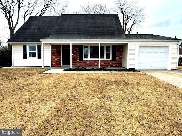 view of front of house with an attached garage, a front yard, and brick siding