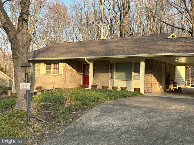 single story home featuring an attached carport, brick siding, aphalt driveway, and a shingled roof