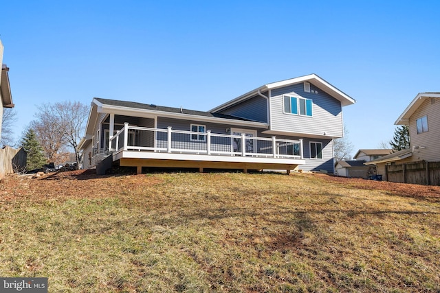 rear view of house with a wooden deck, fence, and a yard