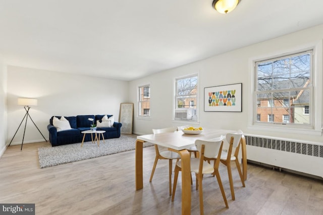 dining space with radiator, baseboards, breakfast area, and wood finished floors