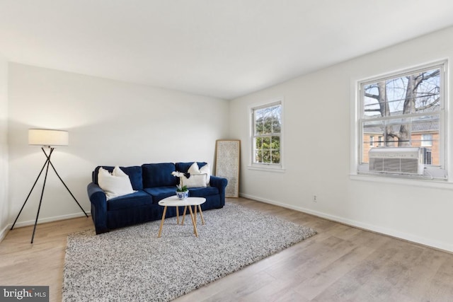 living room featuring cooling unit, baseboards, and wood finished floors