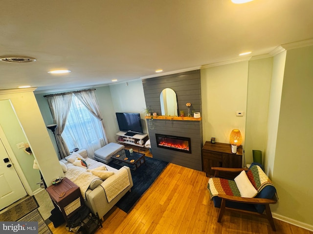 living room with visible vents, ornamental molding, wood finished floors, a large fireplace, and baseboards