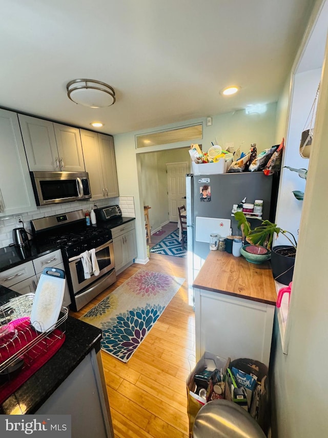 kitchen featuring tasteful backsplash, light wood-style floors, appliances with stainless steel finishes, and a toaster