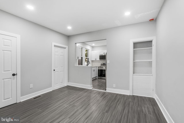 interior space with a sink, recessed lighting, dark wood finished floors, and baseboards