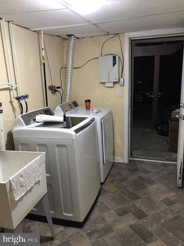 laundry area featuring laundry area, separate washer and dryer, a sink, and stone finish flooring