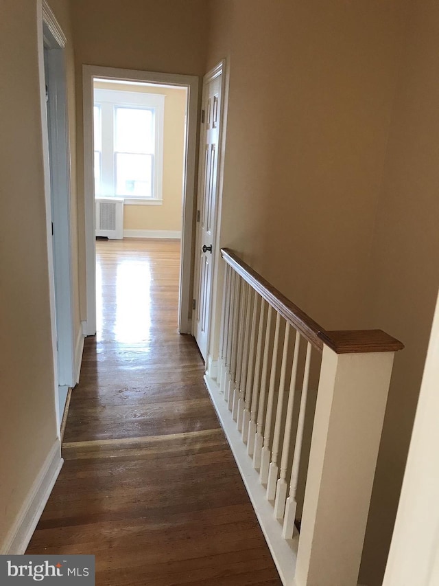 hall with radiator, dark wood finished floors, and baseboards