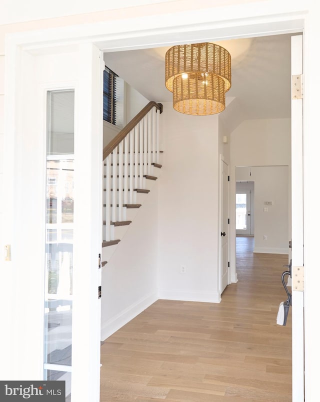 entrance foyer with a notable chandelier, baseboards, light wood-style floors, and stairs