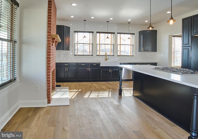 kitchen featuring backsplash, light countertops, light wood-style floors, stainless steel appliances, and a sink