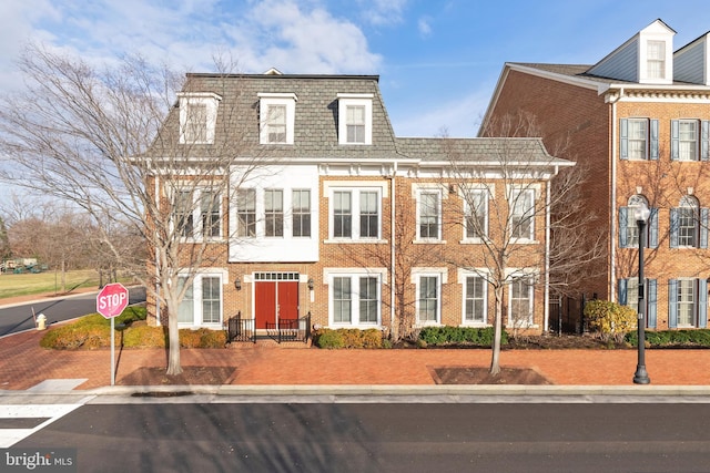 view of front of house featuring brick siding and mansard roof