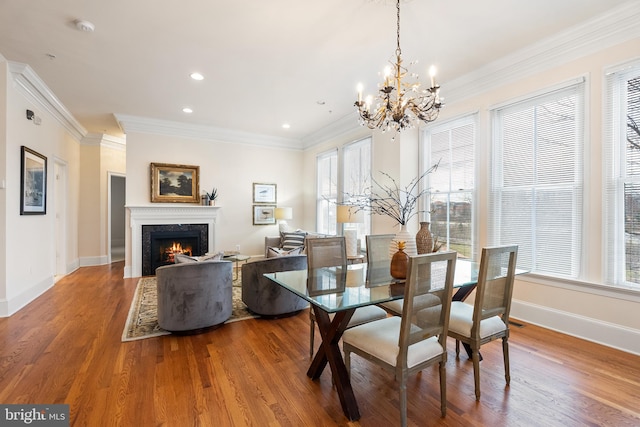 dining area featuring baseboards, crown molding, a premium fireplace, and wood finished floors