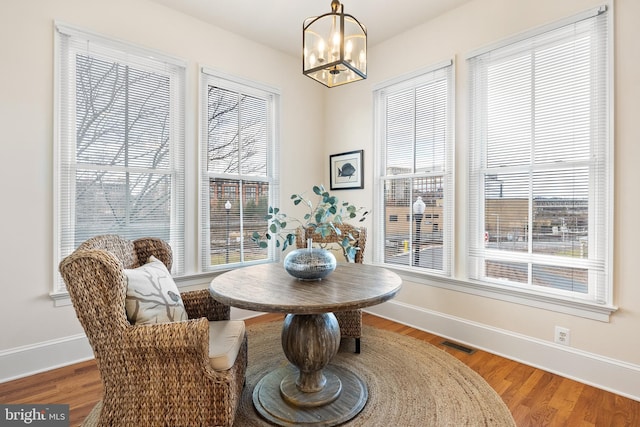 dining area with an inviting chandelier, baseboards, visible vents, and wood finished floors