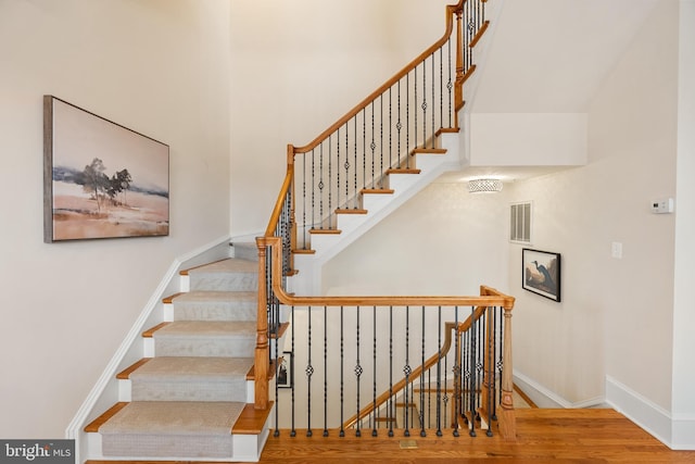 stairway with visible vents, baseboards, and wood finished floors