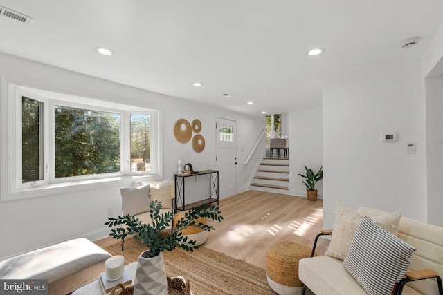 living area featuring light wood-style flooring, recessed lighting, visible vents, baseboards, and stairway