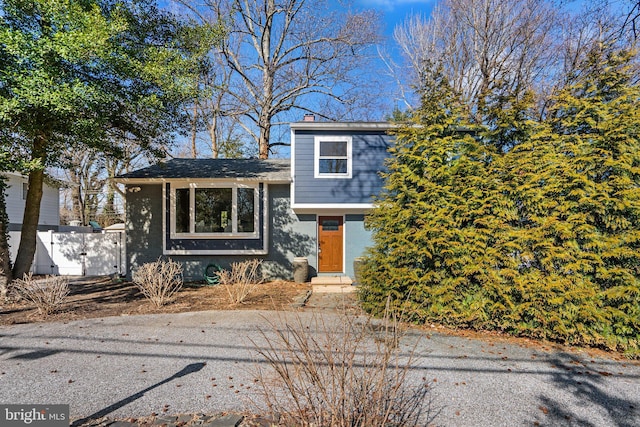 tri-level home with fence and a chimney