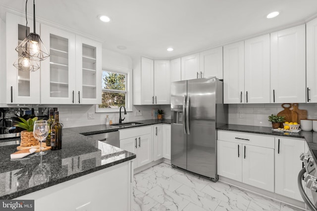 kitchen featuring decorative light fixtures, stainless steel appliances, glass insert cabinets, white cabinets, and a sink