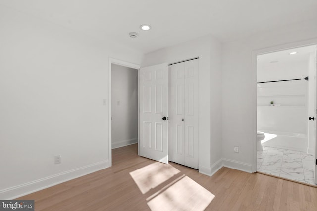 unfurnished bedroom with marble finish floor, recessed lighting, a closet, connected bathroom, and baseboards