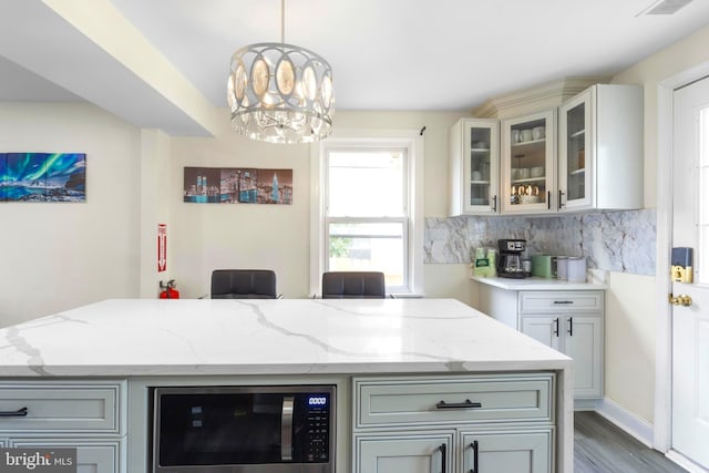 bar featuring a chandelier, dark wood-type flooring, decorative backsplash, stainless steel microwave, and decorative light fixtures