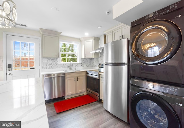 washroom with laundry area, a sink, visible vents, light wood-style floors, and stacked washer / drying machine