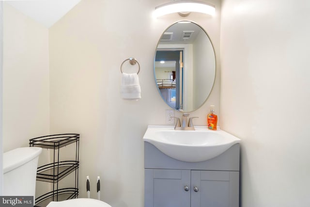 half bathroom featuring visible vents, vanity, and toilet