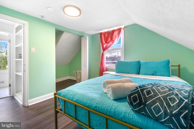 bedroom with a textured ceiling, multiple windows, baseboards, and dark wood-style flooring