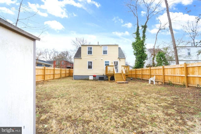 rear view of house featuring a fenced backyard, a deck, and a lawn