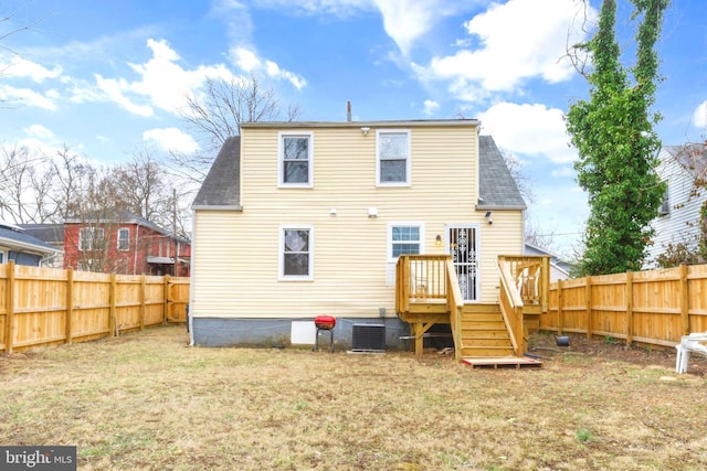 rear view of house featuring a fenced backyard, a yard, stairway, and central air condition unit