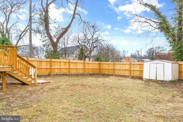 view of yard with an outbuilding, a fenced backyard, stairway, and a shed