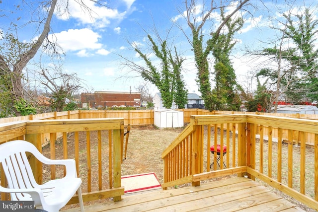 wooden terrace with a storage shed, an outdoor structure, and a fenced backyard