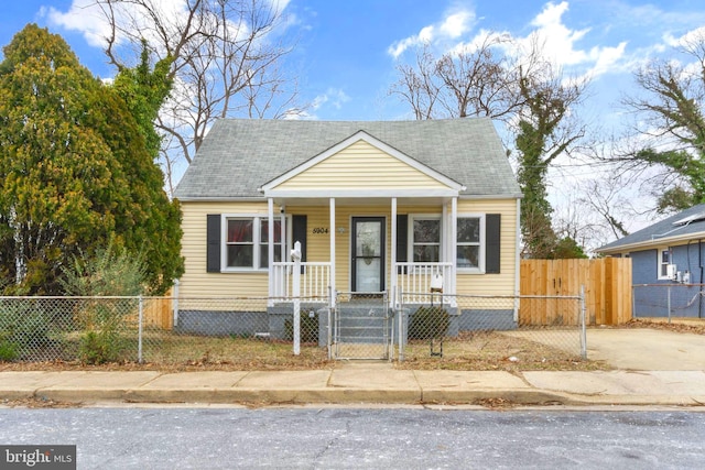 view of front facade featuring covered porch, a fenced front yard, a gate, and roof with shingles