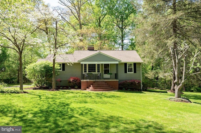 ranch-style home featuring a shingled roof, a front yard, covered porch, and a chimney