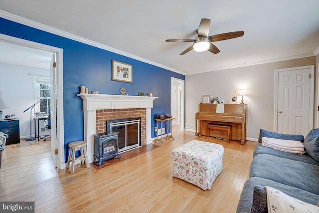 living area featuring a ceiling fan, baseboards, ornamental molding, and wood finished floors