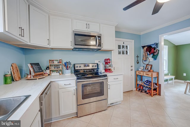 kitchen with stainless steel appliances, white cabinets, ornamental molding, and light tile patterned flooring