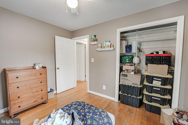 bedroom featuring ceiling fan, a closet, baseboards, and wood finished floors