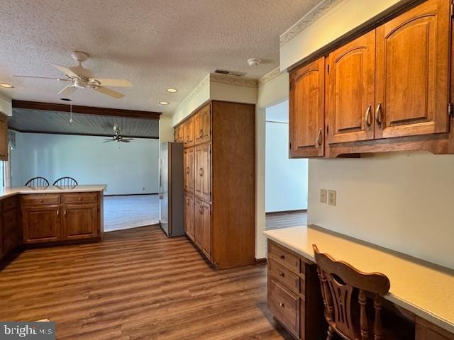 kitchen with dark wood-style floors, light countertops, brown cabinetry, and built in study area