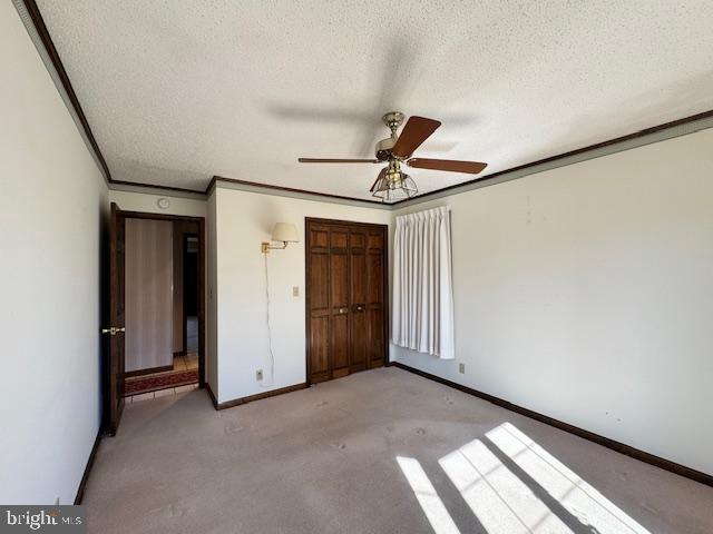 unfurnished bedroom featuring a closet, crown molding, a textured ceiling, and baseboards