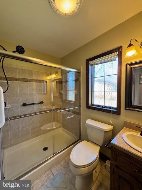 bathroom featuring toilet, a shower stall, vanity, and tile patterned floors