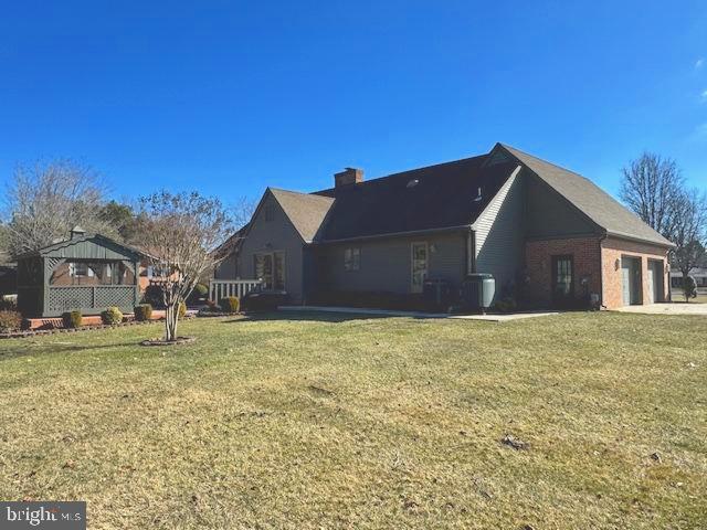 view of side of property with a chimney, a gazebo, a lawn, and an attached garage