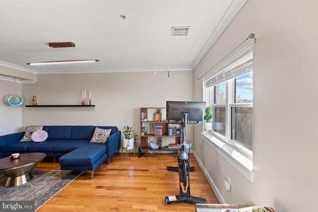 exercise room with baseboards, wood finished floors, visible vents, and crown molding