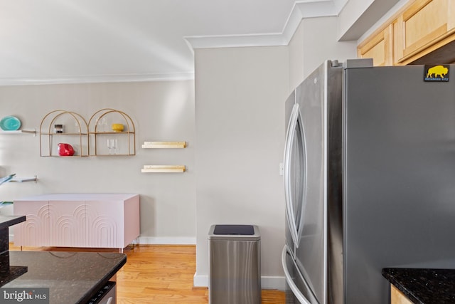 kitchen with ornamental molding, freestanding refrigerator, dark stone counters, and light brown cabinets