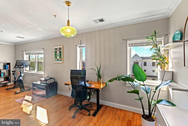 office area featuring ornamental molding, a wealth of natural light, visible vents, and light wood finished floors