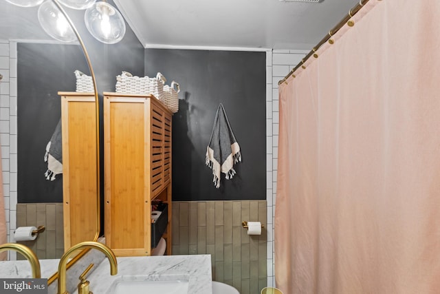 full bath featuring toilet, vanity, tile walls, and wainscoting