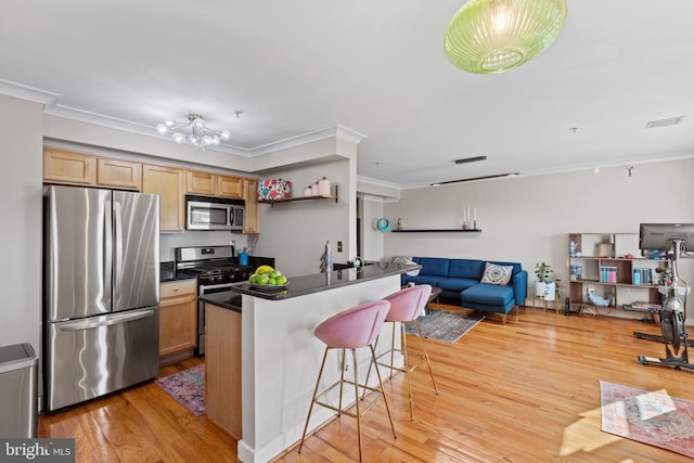 kitchen with stainless steel appliances, dark countertops, light brown cabinetry, open floor plan, and a kitchen bar