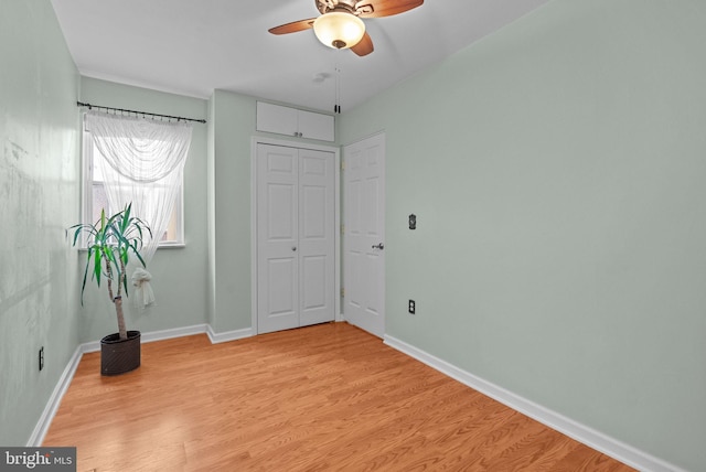 unfurnished bedroom with ceiling fan, light wood-style flooring, and baseboards