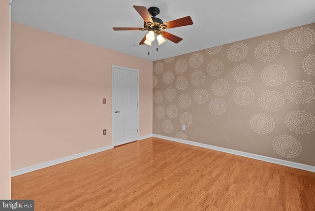 spare room with ceiling fan, light wood-style flooring, and baseboards